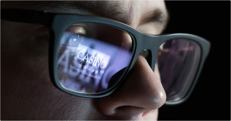 person looking at the screen playing online casinos on a dark background
